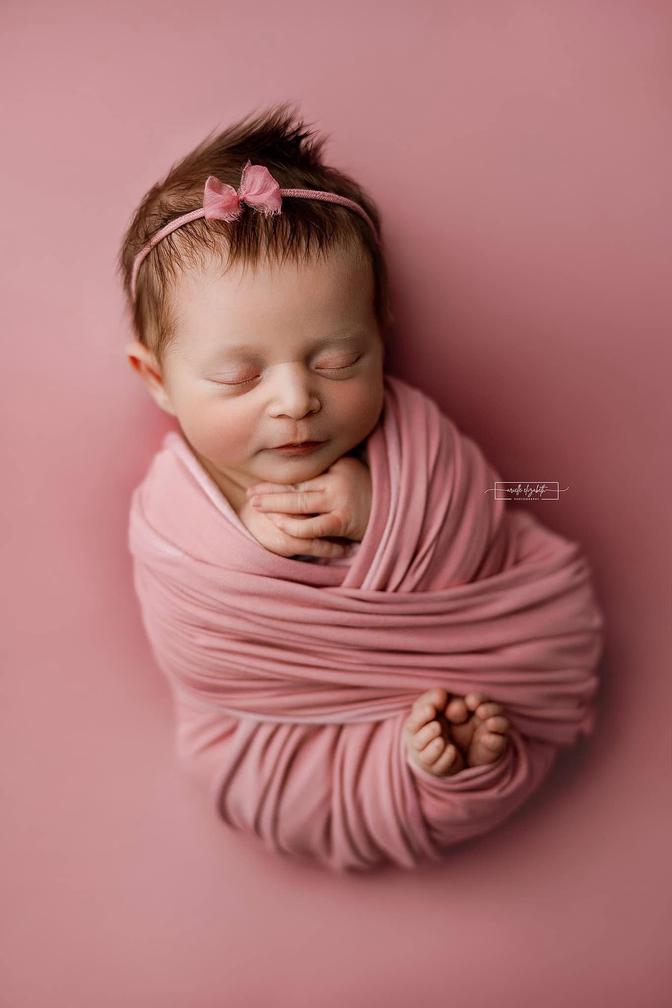 Chandler Pinkypie a pink newborn photography backdrop draped on a posing table or beanbag, that is a smooth, stretchy and soft fabric for beautiful baby portraits. Credit Arielle Elizabeth Photography