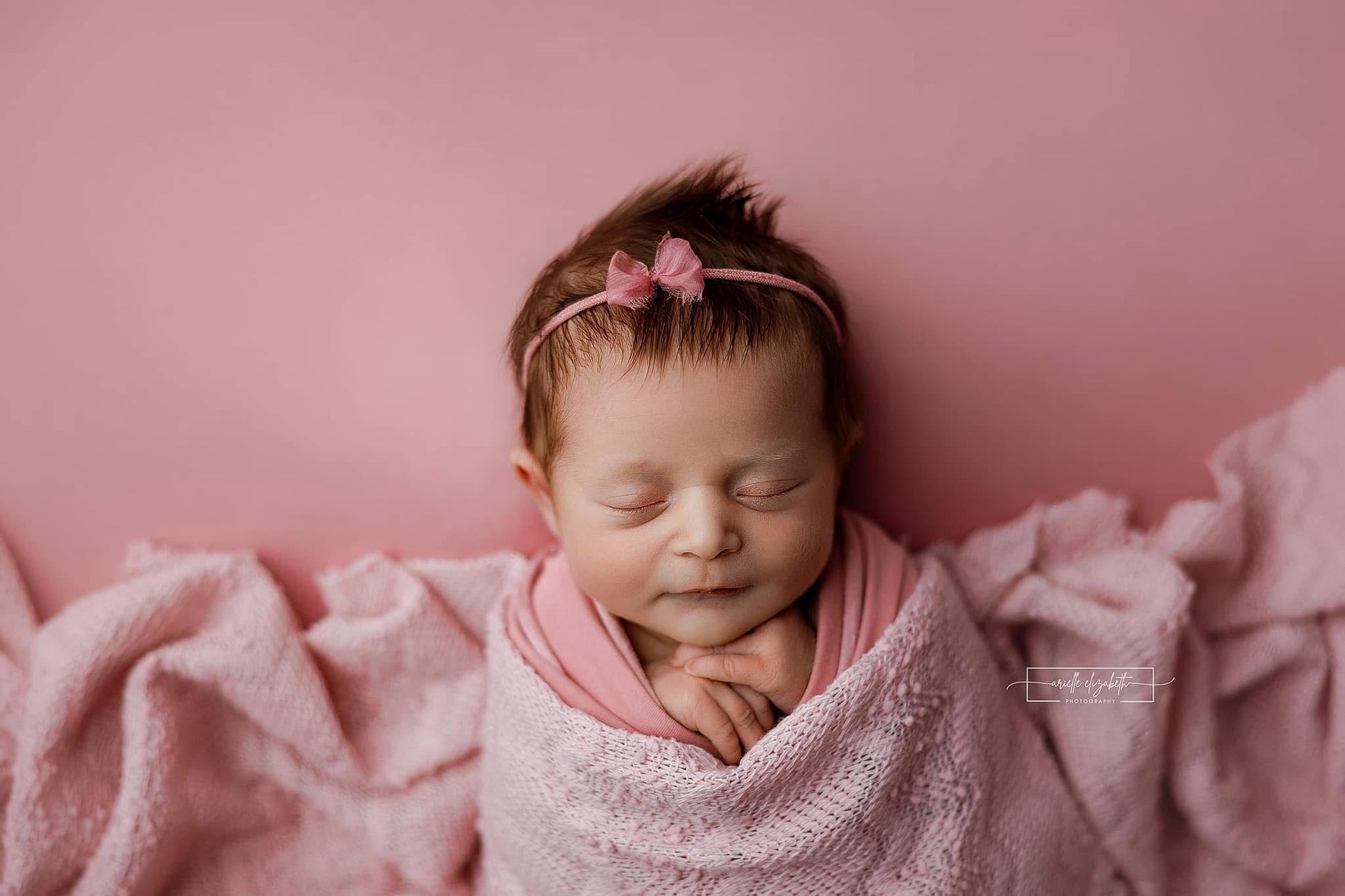 Chandler Pinkypie a pink newborn photography backdrop draped on a posing table or beanbag, that is a smooth, stretchy and soft fabric for beautiful baby portraits. Credit Arielle Elizabeth Photography
