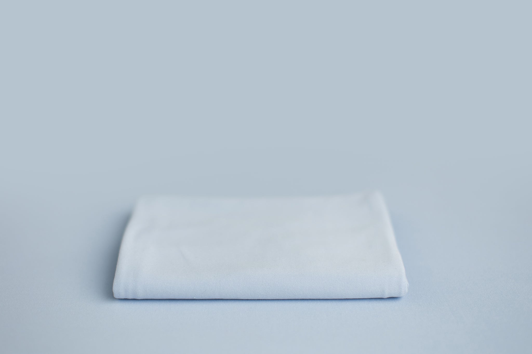 Chandler Baby Blues a light blue newborn photography backdrop draped on a posing table or beanbag, that is a smooth, stretchy and soft fabric for beautiful baby portraits.