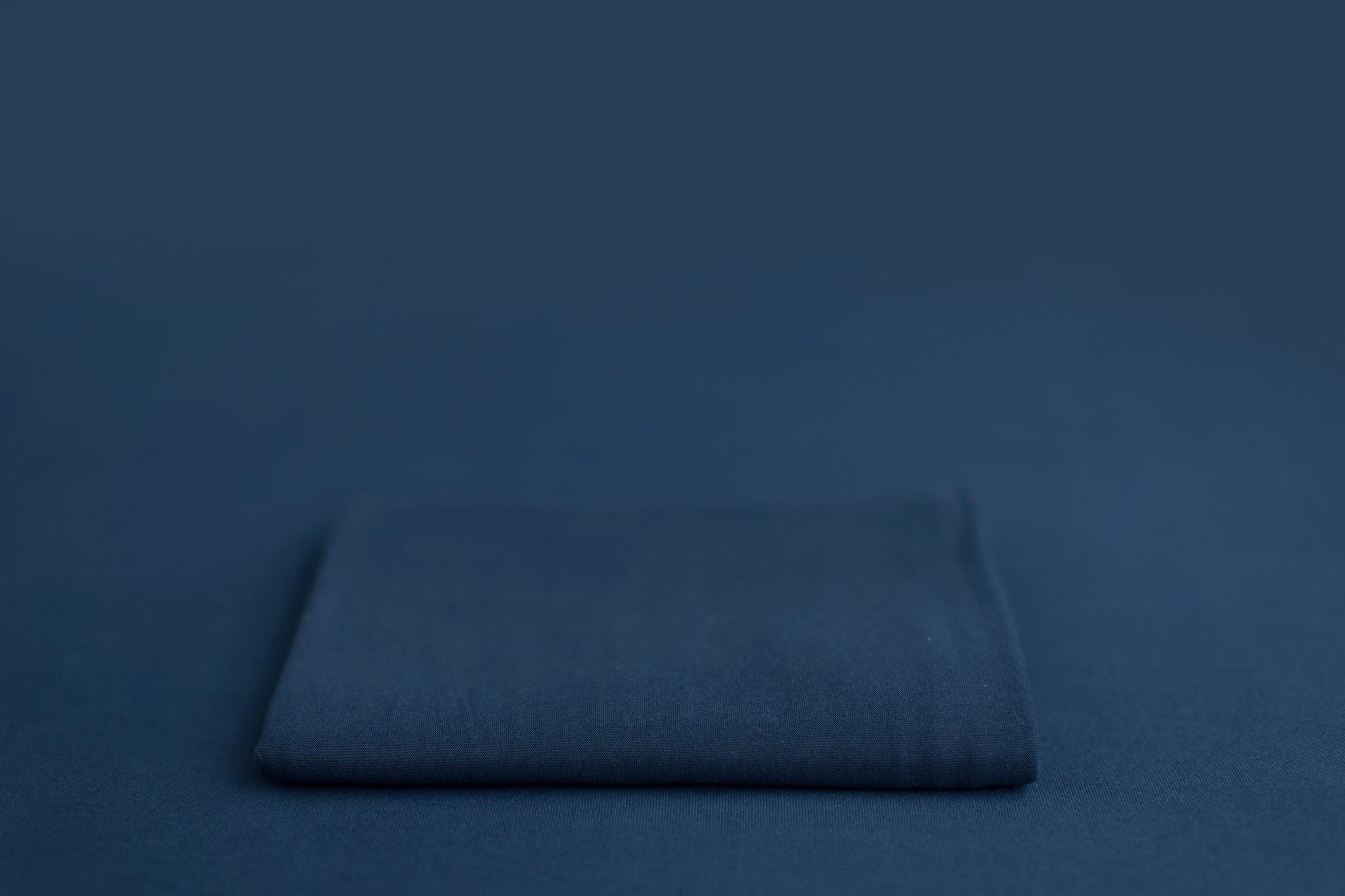 Chandler Blue Lagoon a blue newborn photography backdrop draped on a posing table or beanbag, that is a smooth, stretchy and soft fabric for beautiful baby portraits.
