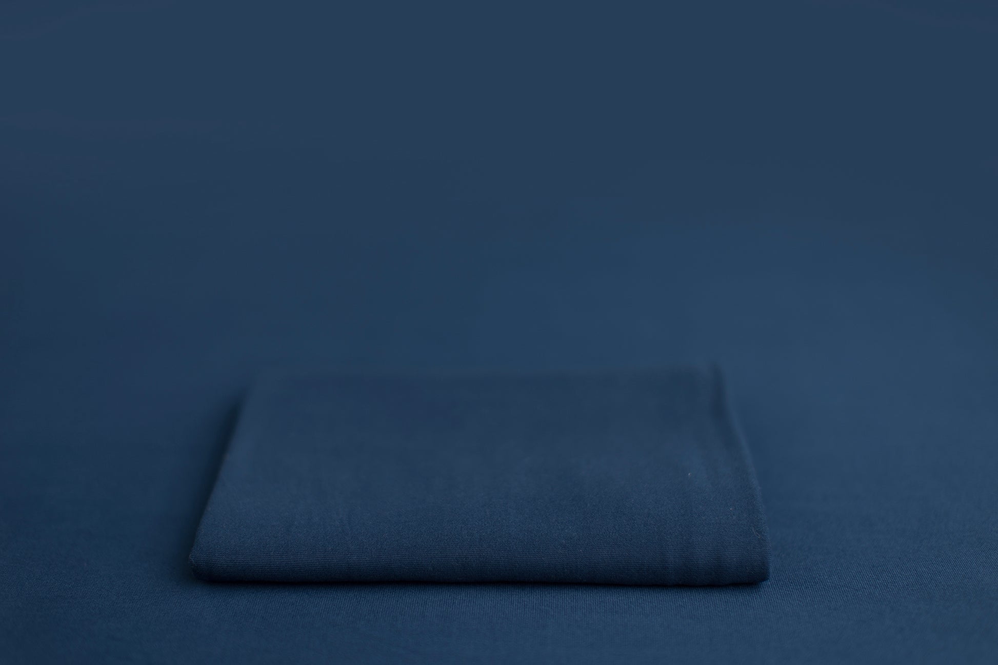 Chandler Blue Lagoon a blue newborn photography backdrop draped on a posing table or beanbag, that is a smooth, stretchy and soft fabric for beautiful baby portraits.