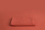 Chandler Rouge a deep pink leaning orange newborn photography backdrop draped on a posing table or beanbag, that is a smooth, stretchy and soft fabric for beautiful baby portraits.